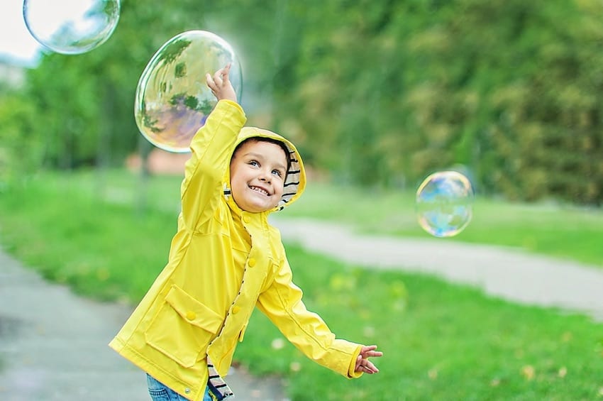 Child playing with bubbles outdoors