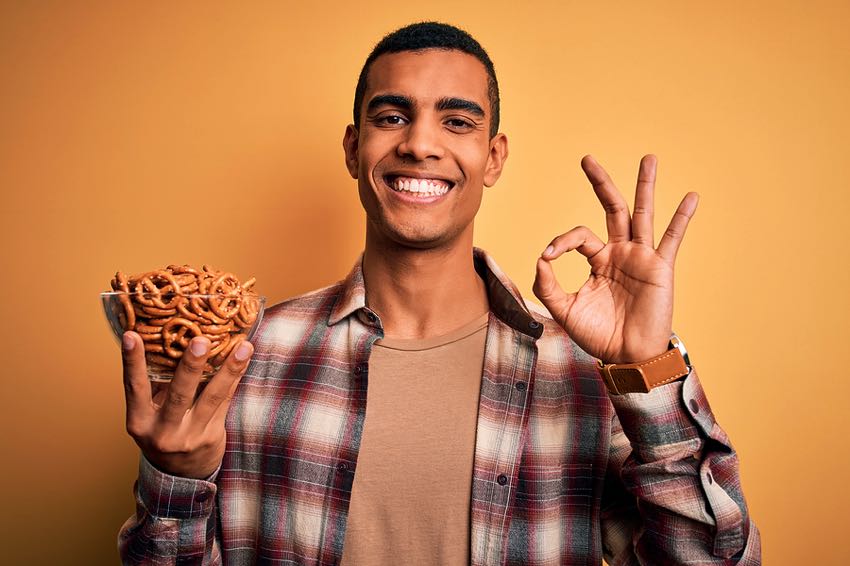 Happy man with bowl of vegan pretzels