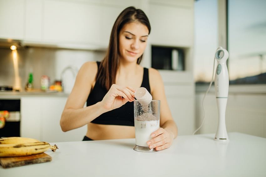 Young woman adding protein to her shake