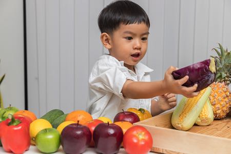 Cute young boy with vegetables
