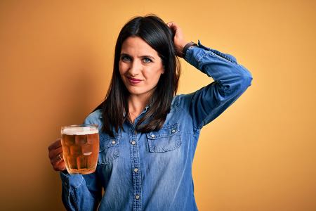 Young woman holding beer looking confused